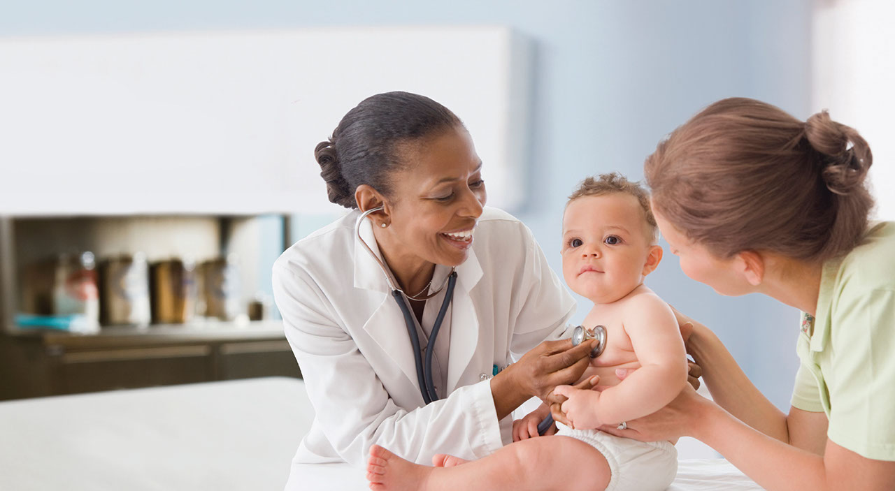 Doctor checking baby heart beat while mom holds baby in a sitting up position