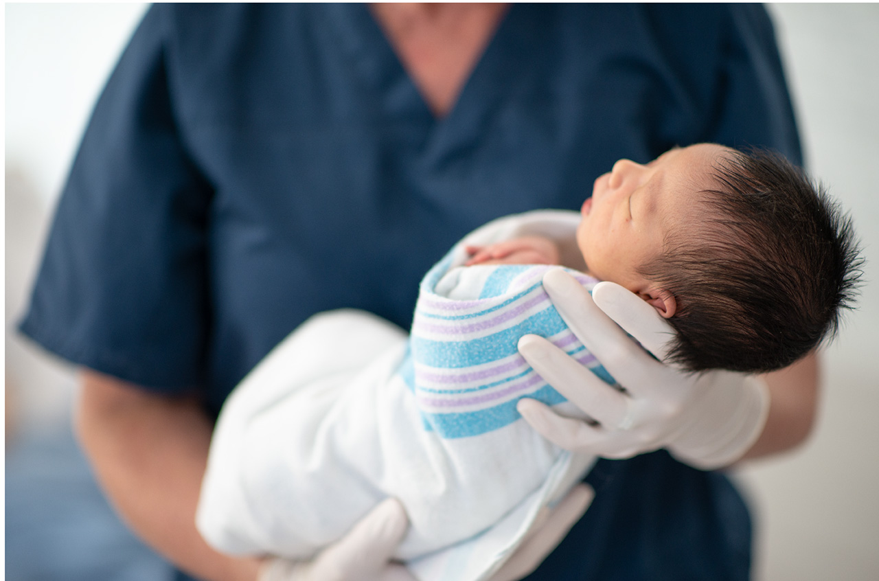 Unrecognizable mother holding the foot of her newborn baby, close up of hand and foot.