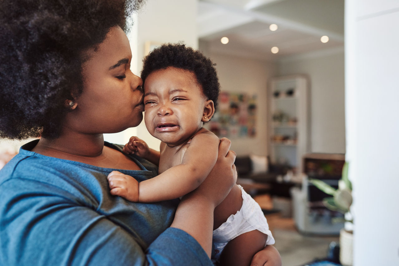Smiling doctor taking the heartbeat of a happy baby with a stethoscope