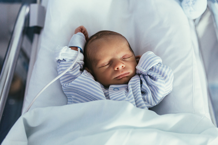 Premature infant sleeping in a hospital bed