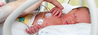 A mother touching the hand of a premature infant asleep in a incubator
