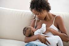 Mother peacefully breastfeeding her baby on couch