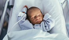 A premature infant sleeping in a hospital bed