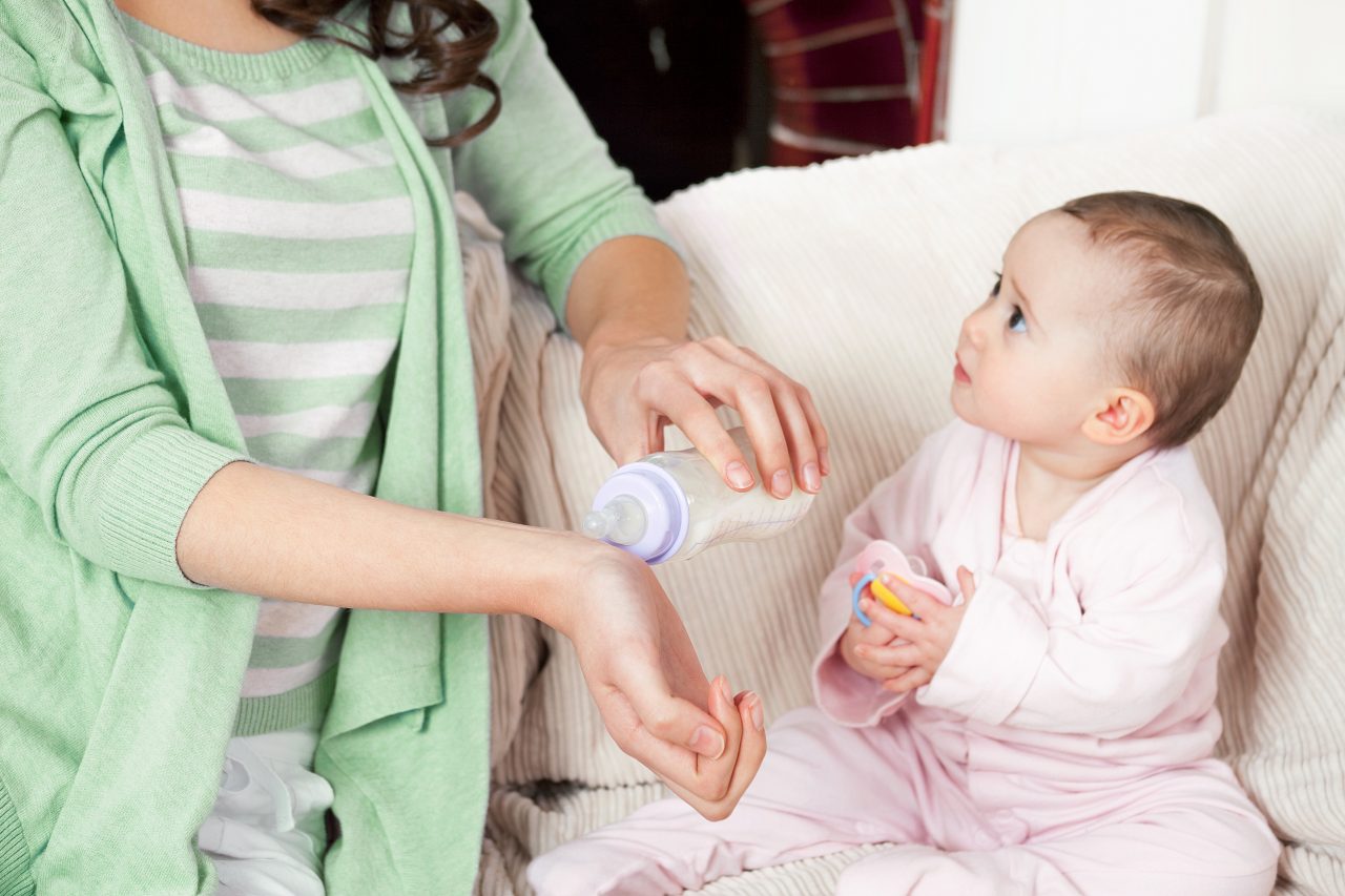 Mother testing milk temperature on wrist