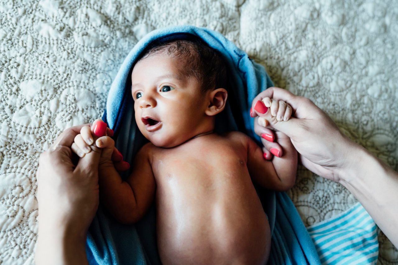 Mother holding newborn's hands while baby lays on blanket  Breastfeeding Education: Tips & Techniques for Getting Started