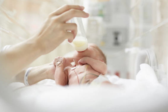Premature baby drinking milk from a bottle while in the Nicu
