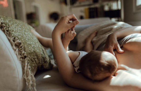 Mother breast feeding baby while laying down