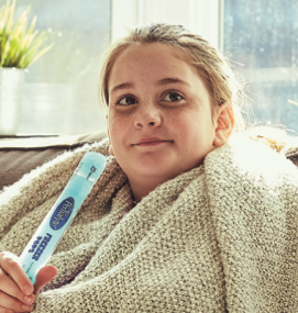 young girl wrapped in a blanket eating a frozen pedialyte pop